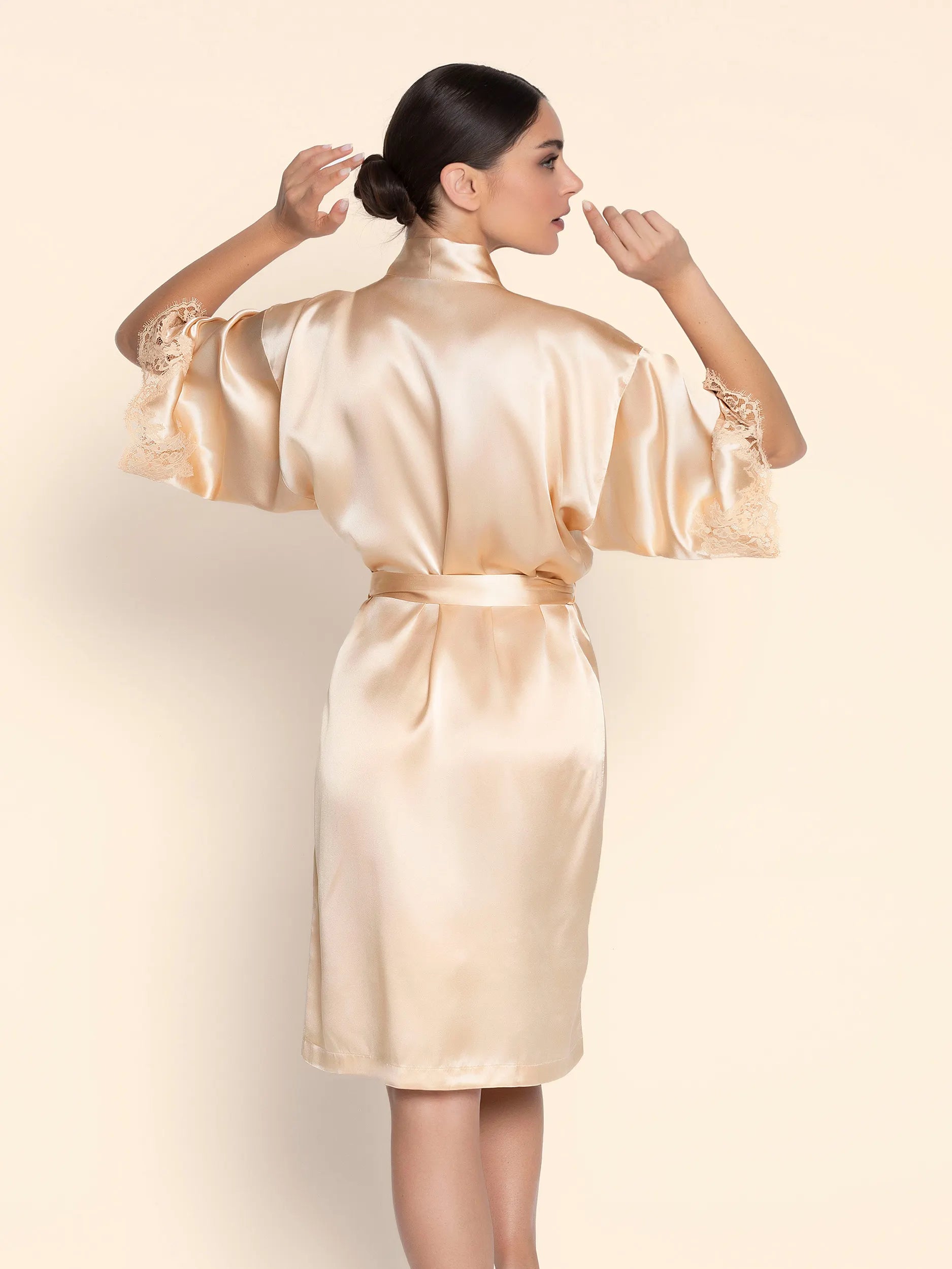 Woman wearing a beige satin robe against a plain background