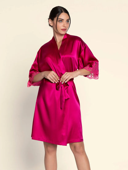 Woman wearing a bright pink satin robe on a beige background