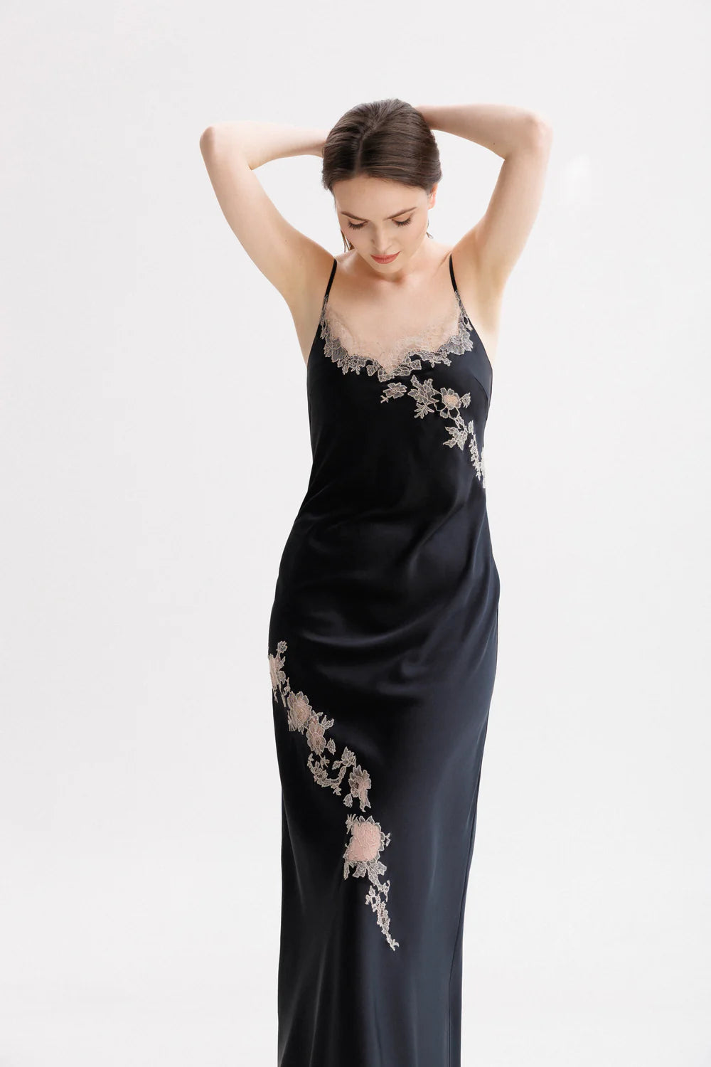 Woman wearing a black silk maxi slip dress with Leavers Lace details. Spaghetti strap stile 