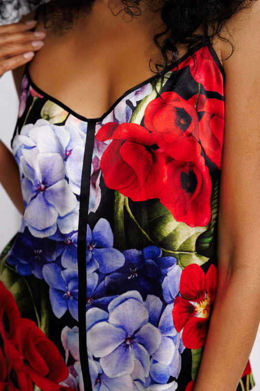 Close-up of a floral silk set of top and shorts  with red and blue flowers on a black background.