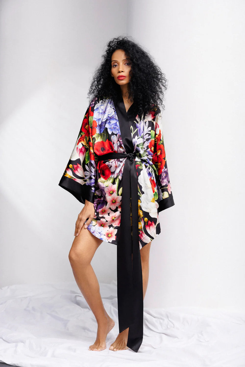 Woman wearing a colorful floral silk kimono with a wide black belt. Showing the front full picture.